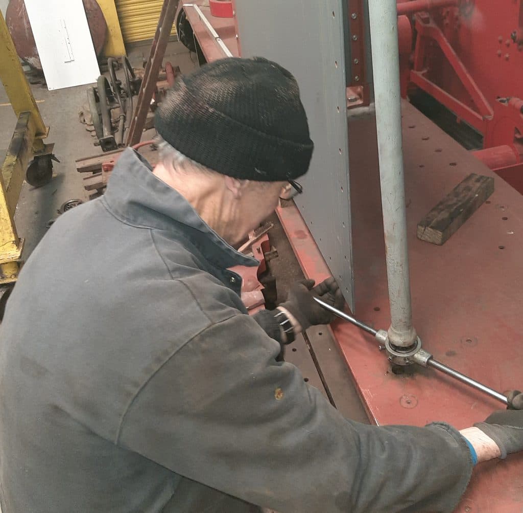John Dixon uses a die nut to clean up the threads on one of Caliban's cab stanchions.